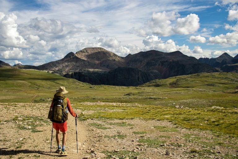 Hiker on a trail with mountains in the distance